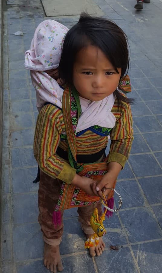 A girl carrying her brother on her back in Sa Pa, Vietnam